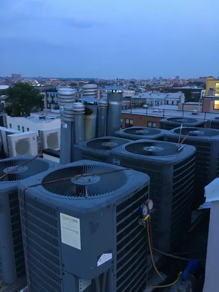 Rooftop condensers at dusk with the city skyline behind them
